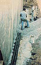 Gravel is spread around the drainpipes that lie against the back wall.